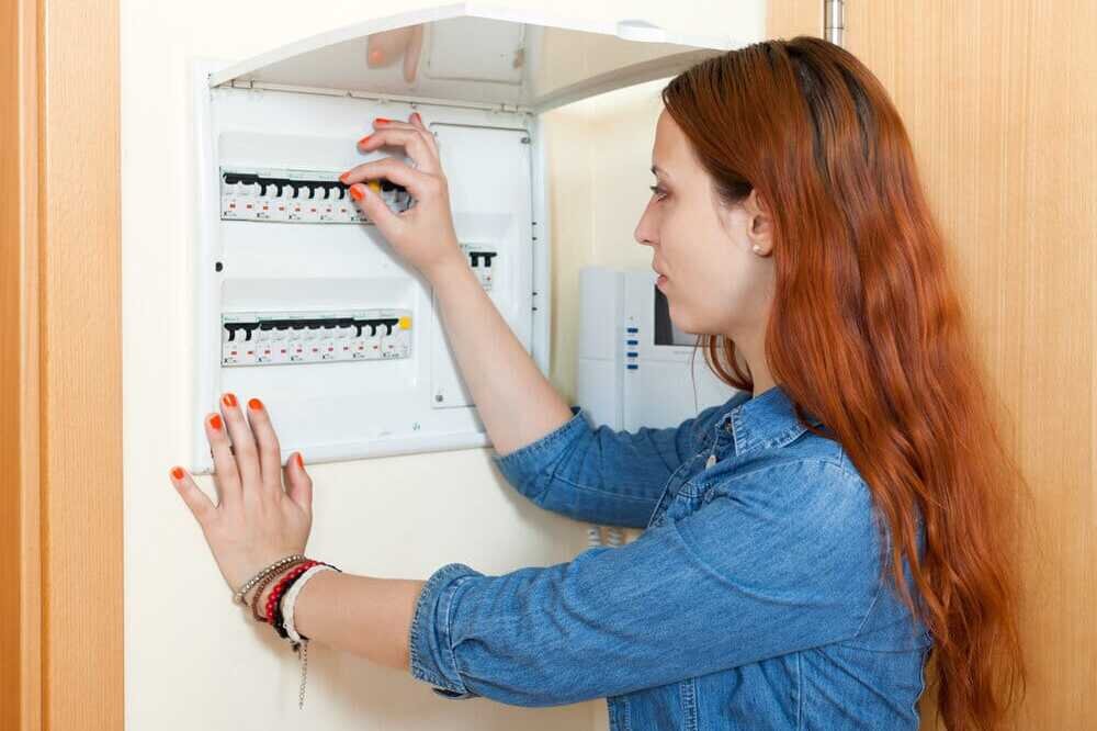homeowner flipping circuit breakers on her electrical panel