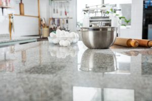 Mixing bowl with eggs and rolling pin on countertop in kitchen