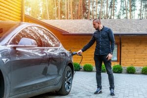 man charging electric vehicle at home