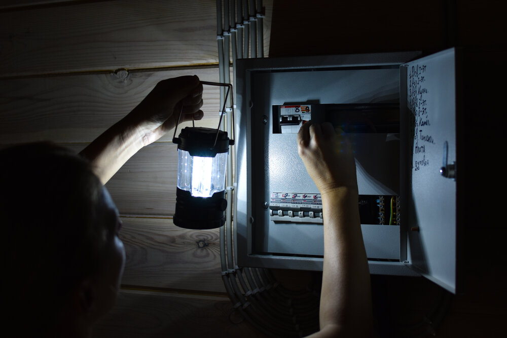 homeowner holding lantern to see circuit breakers in the dark
