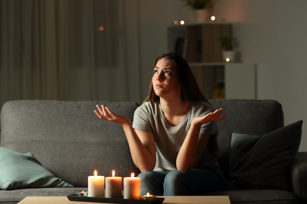 Woman complaining during a power outage sitting on a couch in the living room at home
