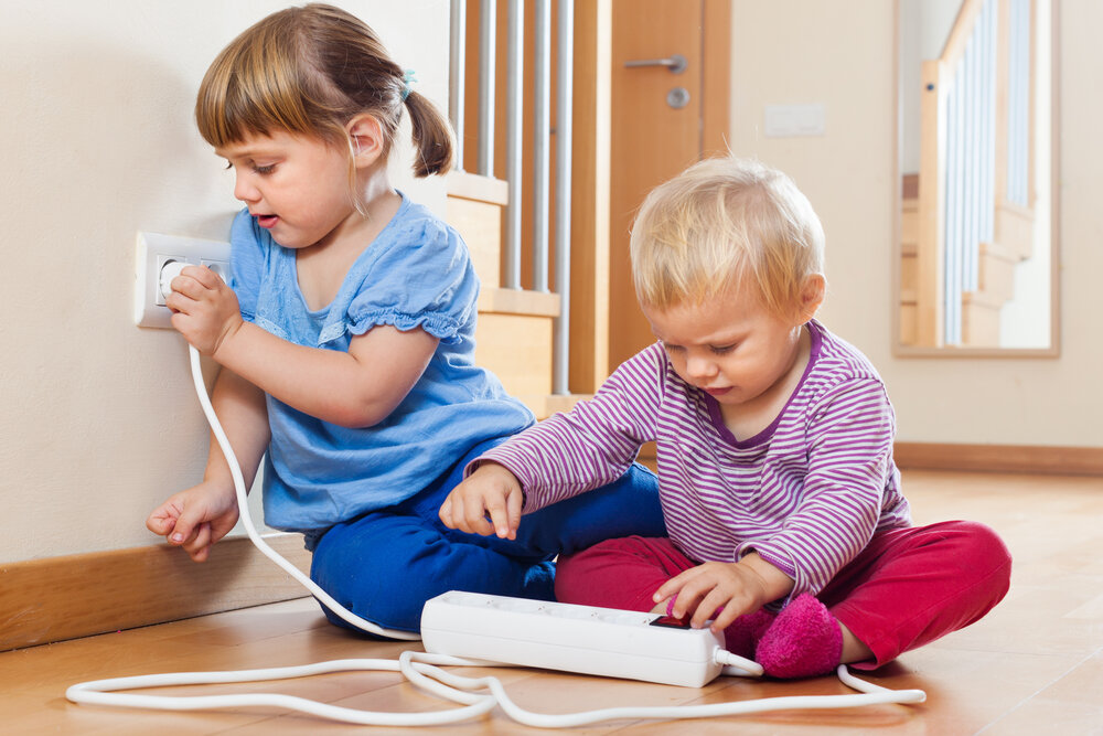 Two children playing with electricity on floor at home