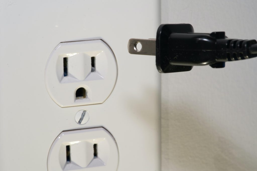 A plug about to be inserted into one of two outlets