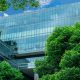 Eco-friendly building in the modern city. Sustainable glass office building with trees for reducing heat and carbon dioxide. Office building with green environment. Smart technology concept.