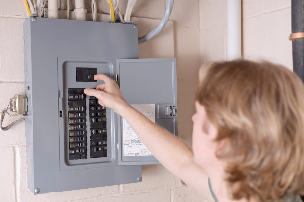 Electrician examining the different types of circuit breakers installed in electrical panel