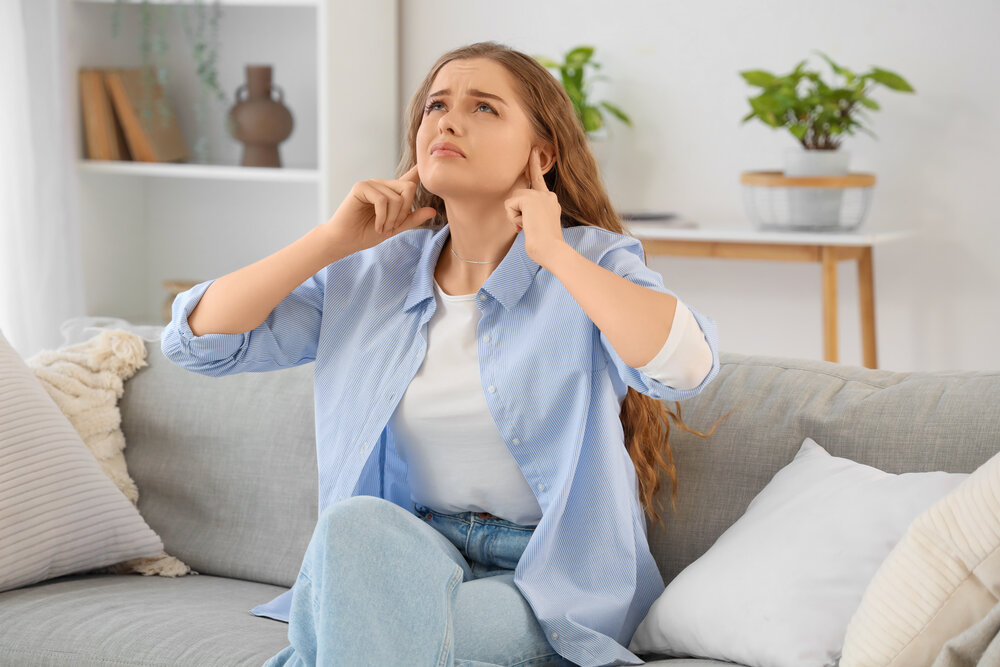 Young woman suffering from buzzing sound coming from electrical panel