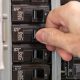 Male electrician turning off power for electrical outlet at circuit breaker box. Resetting tripped breaker in residential electricity power panel.