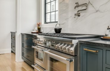 Transitional Kitchen with Stainless Steel Luxury Appliances. Transitional kitchen design with marble backsplash. Styled counter and stove with pot filler.
