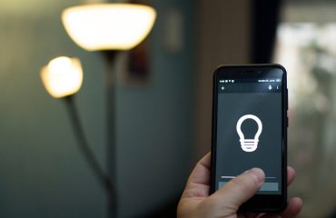 Smart home: man controlling lights with app on his phone. electric concept.