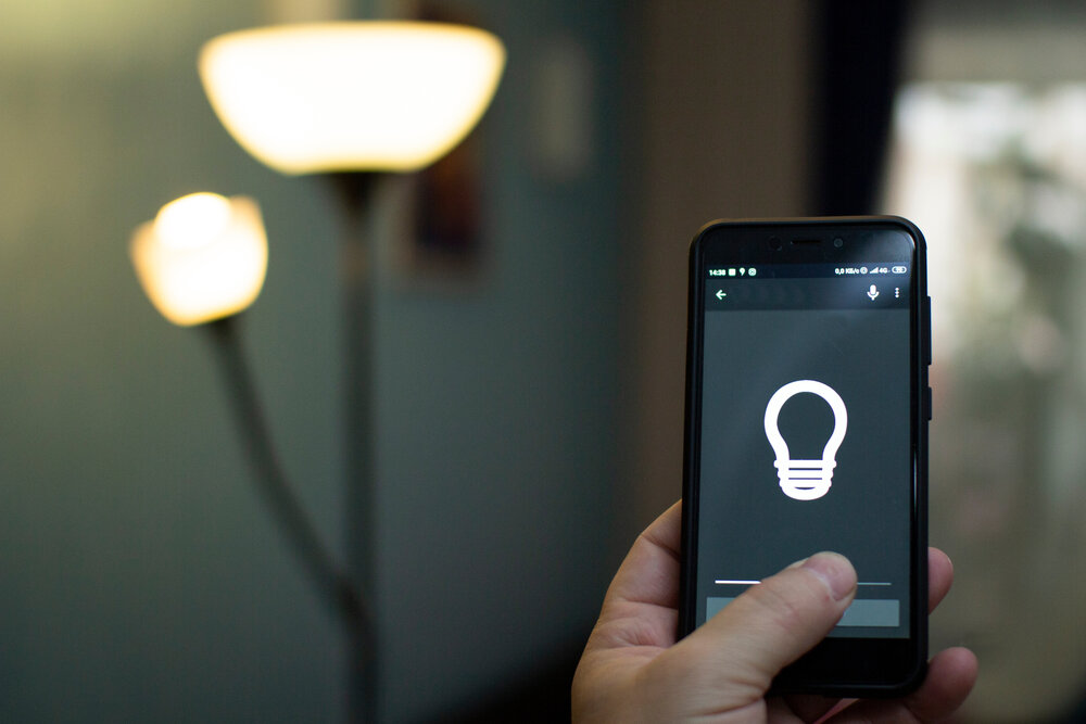 Smart home: man controlling lights with app on his phone. electric concept.