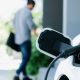 Focus EV charging station at home with blur progressive man in background.